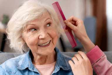 Caregiver combing elderly patient's hair
