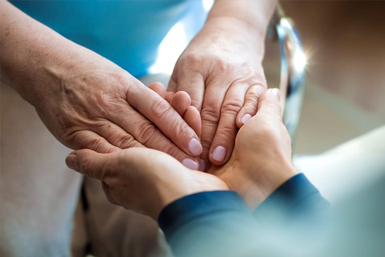 Caregiver holding patient's hands