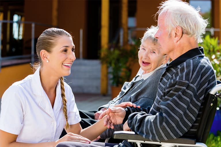 Caregiver talking to elderly couple