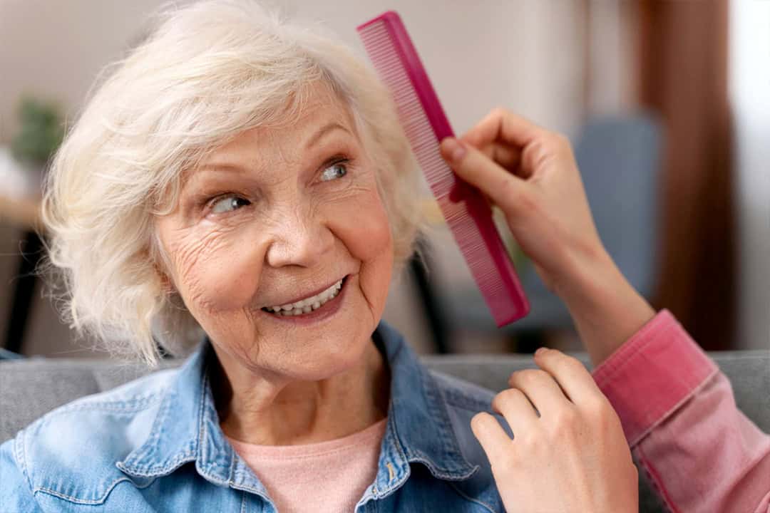 Caregiver combing elderly women's hair